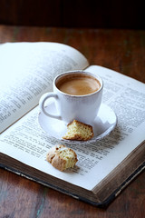 Cup of coffee and old book on rustic background.  