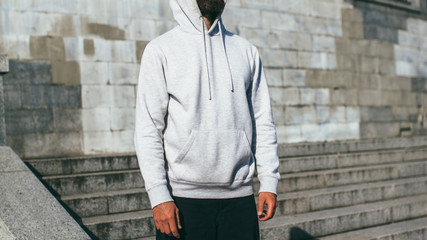 City portrait of handsome hipster guy with beard wearing gray blank hoodie or hoody with space for...