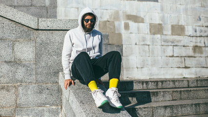 City portrait of handsome hipster guy with beard wearing gray blank hoodie or hoody with space for...