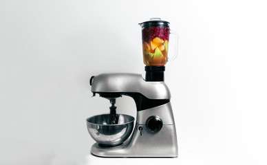 Smoothie Mixer mit bunten Früchten, Küchenmaschine vor weißem Hintergrund mit farbenfrohen Früchten