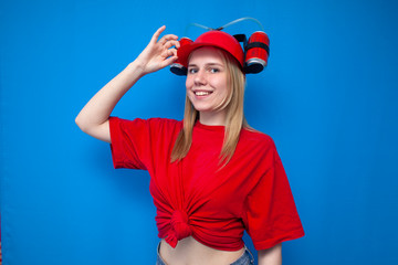 portrait of a young female fan girl in red uniform on a blue background, a cheerleader with a beer hat
