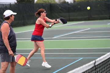 Plakat A pickleball two-handed backhand is hit by a senior during a doubles match