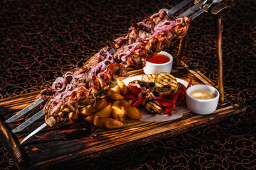 Skewers on skewers with potatoes and sauces.