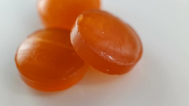 Orange lozenges for sore throats. Lozenge extreme close-up. Real time, troche on a white background.