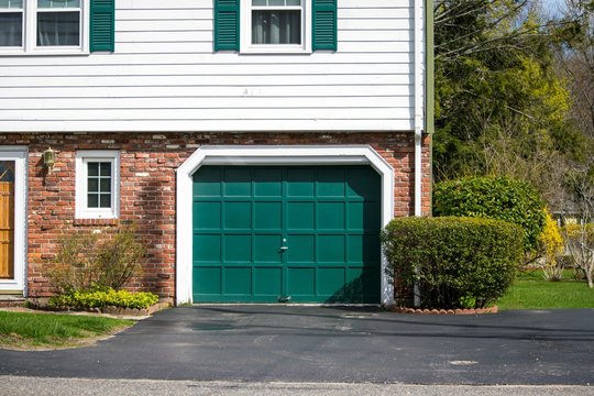 One Car Garage Door Painted In Green Color In A Single Residential House