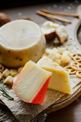 Assorted hard cheeses with pretzels on the cutting Board. On a wooden background, selective focus
