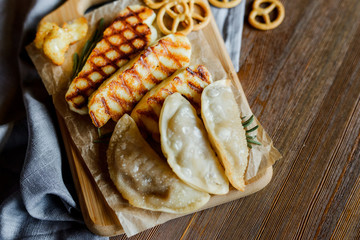 fried halloumi cheese and dumplings with rosemary on a wooden cutting board on wooden table with small pretzels