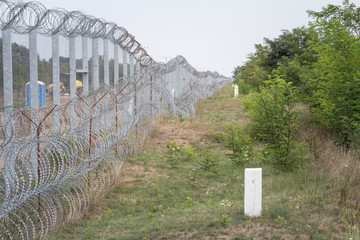 Border fence between Subotica (Serbia) & Kelebia (Hungary) with boundary marker. This border wall...