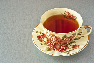 a beautiful Cup of tea with a picture of roses stands on a gray table
