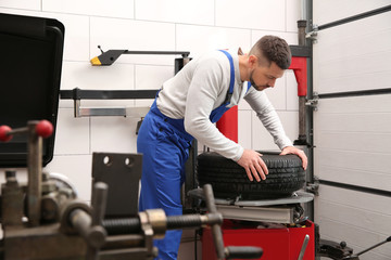 Obraz na płótnie Canvas Mechanic working with tire fitting machine at car service