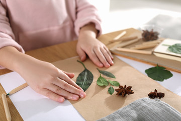 Little girl working with natural materials at table indoors, closeup. Creative hobby