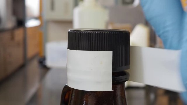 Taping the cover on a chemical storage bottle to prevent vapor leakage.