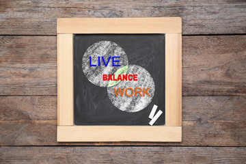 Work-life balance concept. Chalkboard with drawing of intersecting circles on wooden background, top view