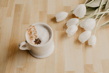 cup of coffee on wooden table white flowers