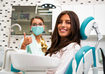 Its safe to go to the dentist in Coronavirus pandemics. Dentist showing thumbs up, while wearing...