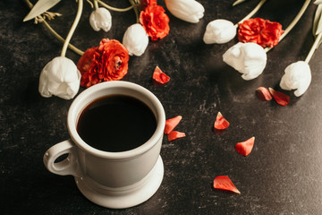 Obraz na płótnie Canvas cup of coffee red and white flowers black background