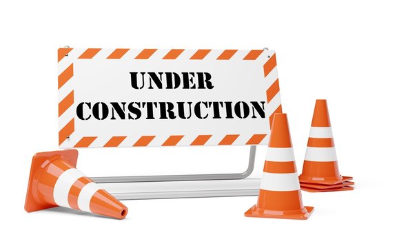 Orange traffic warning cones or pylons with street barrier under construction sign on white background - under construction, maintenance or attention concept