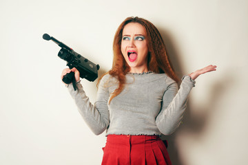 Girl with curled voluminous hair, model with hairstyle in the style of the 80s. 90's smiles, thoughtful. Courses in operator, installation, video filming. A rare old camera.