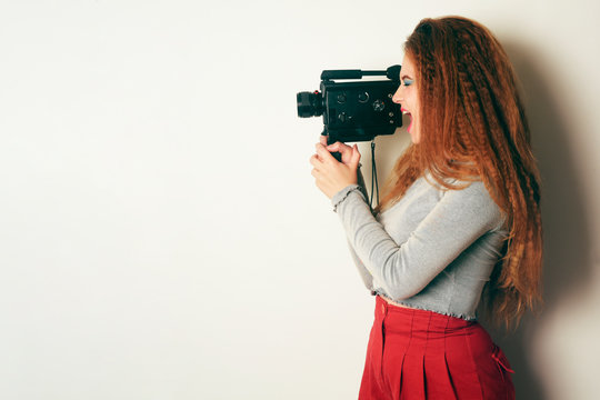 Girl with curled voluminous hair, model with hairstyle in the style of the 80s. 90's, thoughtful. Courses on operator, installation, video filming, a girl takes pictures on a camcorder