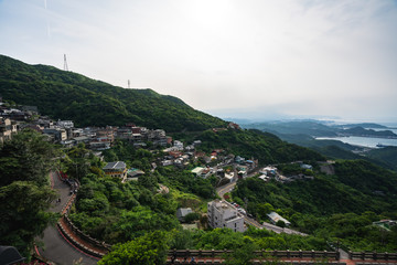 Scenic Panoramic View of Village sitting on the side of a mountain during cloudy weather with a view of distant islands 