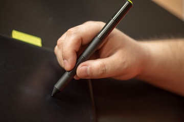 Graphic table and pen in hand of artist