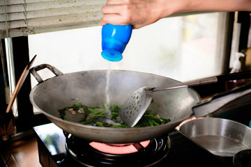 Hand drop flavoring in to cooking pan