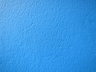 Blue painted exterior wall textured background. Exterior plastered wall of exposed building illuminated by sunlight.
