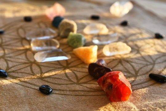 An close up image of chakra balancing crystals on a wooden table with glowing evening sunlight warming the crystals. 