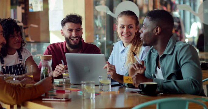 Multi-ethnic group of friends smiling and studying together at cafe