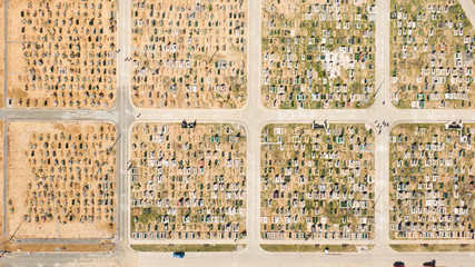 Fototapeta premium Aerial photo of new cemetery graveyard showing the headstones and tombstones of the graves some are with flowers long shadows from the coming sundown