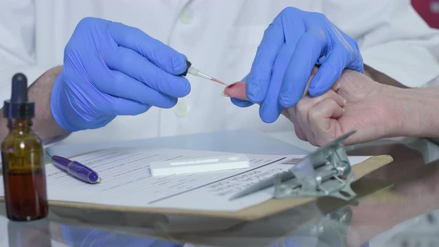 A healthcare worker or laboratory technician using a finger-stick whole blood antibody test kit to quickly determine if this woman has been exposed to COVID19 in the past and has developed antibodies.