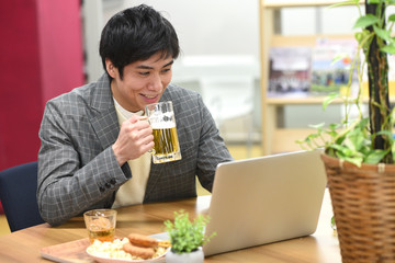 PCを見ながらビールを飲む男性