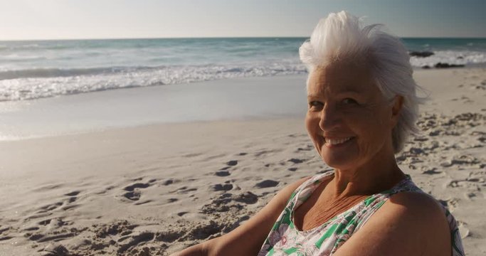 Senior woman sitting looking away at the beach