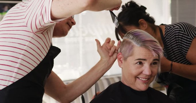 Side view woman having her hair styled by two hairdressers