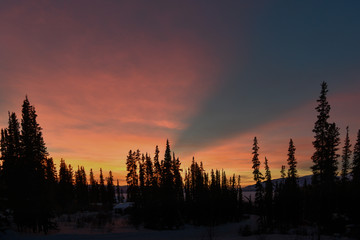 An amazingly beautiful pink, purple & orange sunset with mountain & woods view. Taken in the boreal forest of Canada during fall autumn.