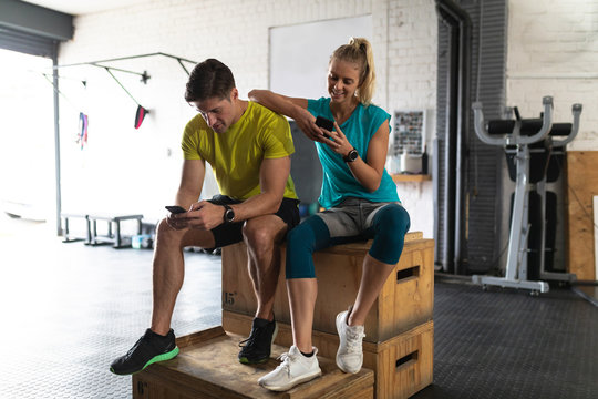 Sporty couple in cross training gym using their phone