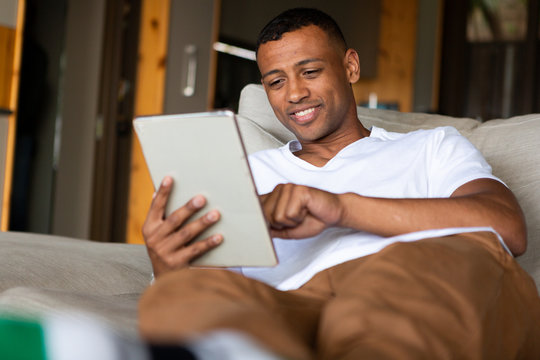 Mixed Race Man using a digital tablet on a sofa