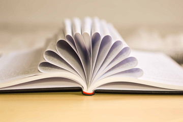 Book with pages folded to form a flower pattern on a wooden texture background