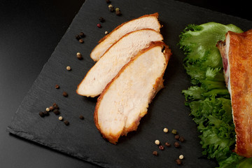 Roasted, sliced chicken breast on a black slate plate.