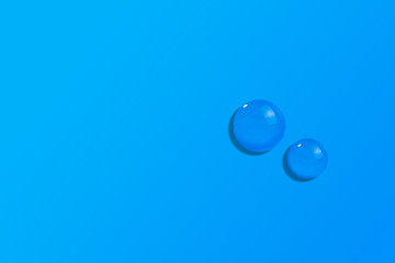 Fluid or transparent liquid gel drops on gradient blue background. Hyaluronic acid sample, snail saliva serum with collagen