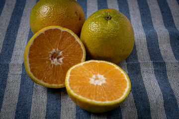whole and halved orange fruits on a table covered with a blue cloth