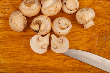 Halves of cut mushrooms and young mushrooms scattered on a wooden background. Close up.