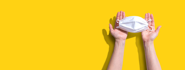 Person holding a white surgical mask overhead view - flat lay