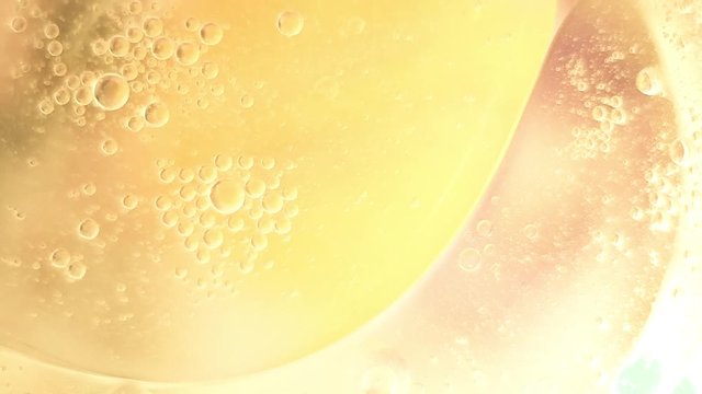 bubbles oil drops in motion on the water surface, yellow abstract background