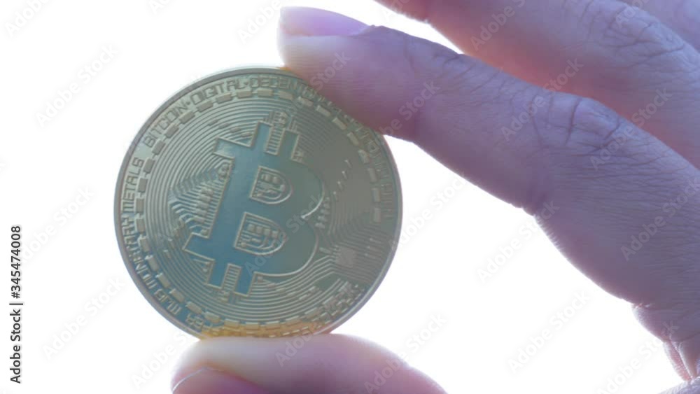 Poster closeup of a hand holding a physical bitcoin with thumb and index finger. virtual currency