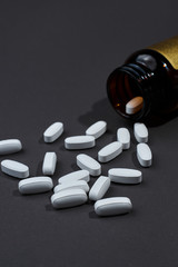 many white tablets on a gray background made of dark glass jars