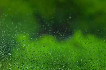 Blurred and focus of rain drop on glass window with green color background in monsoon season for abstract and background concept.