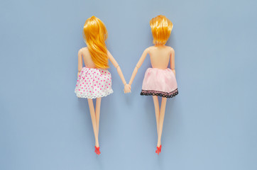 Two female dolls naked on top holding hand with blue background. Pride day and zero discrimination...