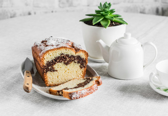 Cozy tea table - homemade cake with nuts and chocolate, teapot, cup, succulent flower on the kitchen table
