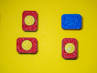 Colored dishwasher tablets on a yellow background. Minimalist design composition